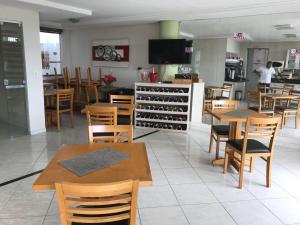a restaurant with tables and chairs and a wine cellar at Hotel Milla in Teixeira de Freitas