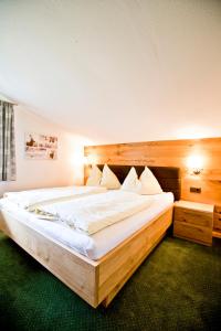 ein großes Bett in einem Schlafzimmer mit einem Kopfteil aus Holz in der Unterkunft Haus Austria in Flachau