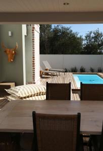 Una mesa de madera con sillas y una piscina. en Cape Coral, en Hermanus