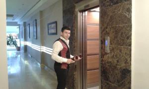 un hombre parado en un pasillo sosteniendo un vaso en Hotel Almina Park, en Duzce