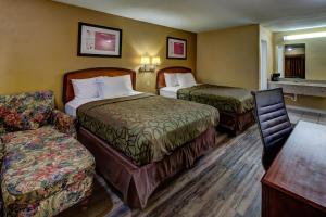 a hotel room with two beds and a chair at Kingsway Inn Corsicana in Corsicana