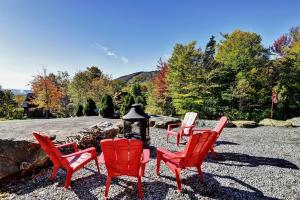 a group of red chairs and a fire place at Chalet 01 Chemin Blanc by Les Chalets Alpins in Stoneham