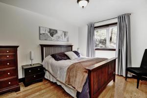 a bedroom with a bed and a chair and a window at Chalet 01 Chemin Blanc by Les Chalets Alpins in Stoneham