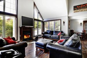 a living room with leather furniture and a fireplace at Chalet 01 Chemin Blanc by Les Chalets Alpins in Stoneham