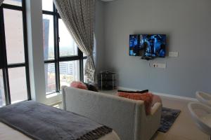 ein Wohnzimmer mit einem Stuhl und einem TV an der Wand in der Unterkunft Pat Luxurious Studio in Gaborone