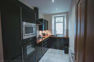 a kitchen with black cabinets and a microwave at Apartment B in Aberdeen