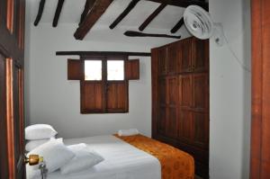 a bedroom with a bed with white sheets and a window at Hospedaje Donde Lorenzo in Barichara