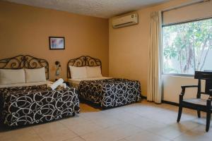 a bedroom with two beds and a window at Hotel Colon Merida in Mérida