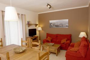 ein Wohnzimmer mit einem roten Sofa und einem Tisch in der Unterkunft Cal Metge de Gualba in gualba de Dalt
