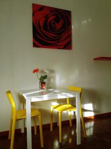 a white table with yellow chairs and a vase with a flower at Bed & Breakfast Anzola in Anzola dell'Emilia