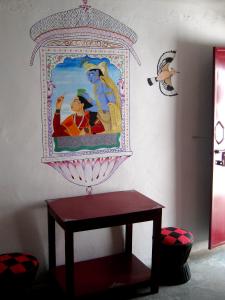 a table in a room with a painting on the wall at Indian Homestay in Khajurāho