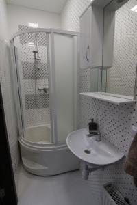 a white bathroom with a shower and a sink at Apelsin apartment in Bila Tserkva