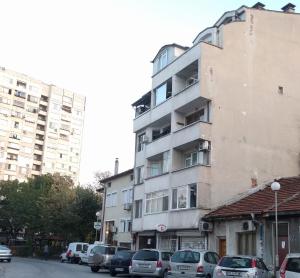 een hoog gebouw met auto's ervoor geparkeerd bij Modern flat near downtown Plovdiv in Plovdiv