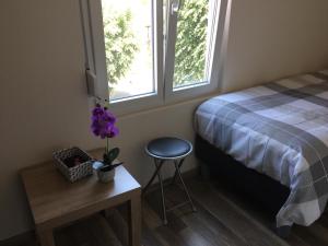 a bedroom with a bed and a stool and two windows at Hotel Restaurant de l'Europe in Wissembourg