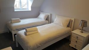 two twin beds in a room with a nightstand and a window at The George & Dragon Felton in Felton