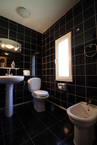 a black tiled bathroom with two toilets and a sink at Sunny Apartment in Predeal +43 photos
