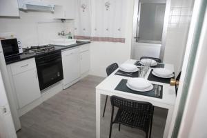 a white kitchen with a table and chairs in it at El Apartamento de María in Lugo