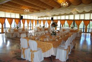 une grande salle de banquet avec des tables et des chaises blanches dans l'établissement Hotel Los Templarios, à Jerez de los Caballeros