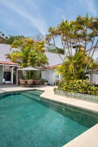 a swimming pool with palm trees and a house at At Buzios House in Búzios