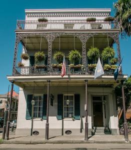 un edificio con balcón y banderas. en Lafitte Hotel & Bar, en Nueva Orleans