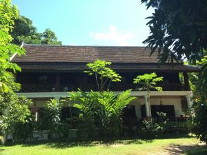 a house in the middle of a yard with trees at Ban Vivanh chambres d'hotes in Luang Prabang