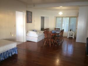 Raina Holiday Accommodation في راروتونغا: غرفة مع طاولة وكراسي وسرير