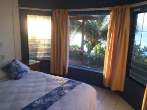 a bedroom with a bed and a large window at Raina Holiday Accommodation in Rarotonga
