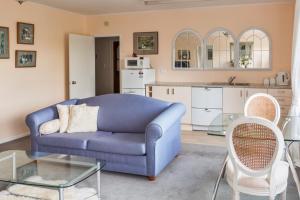 a living room with a blue couch and a kitchen at The Whitehouse of Marybank in Nelson