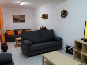 ein Wohnzimmer mit einem schwarzen Sofa und orangefarbenen Kissen in der Unterkunft Painel de Monsaraz in Reguengos de Monsaraz