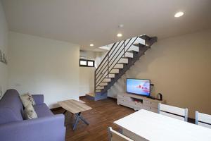 a living room with a purple couch and a staircase at Yi Jia Yuan Homestay in Nanzhuang