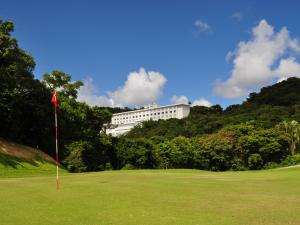 un campo de golf con un edificio blanco en el fondo en Motobu Green Park and Golf Course, en Motobu