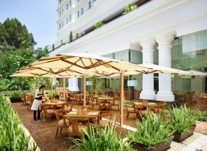 a restaurant with wooden tables and umbrellas at Park Hyatt Saigon in Ho Chi Minh City