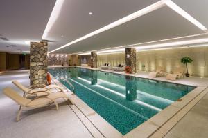 a swimming pool in a hotel with lounge chairs at Swisstouches Guangzhou Hotel Residences in Guangzhou