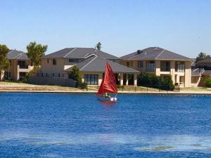 a small sail boat in the water in front of houses at King House in Point Cook