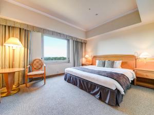 a hotel room with a bed and a desk and a window at Forest Inn Showakan (Okura Hotels & Resorts) in Akishima