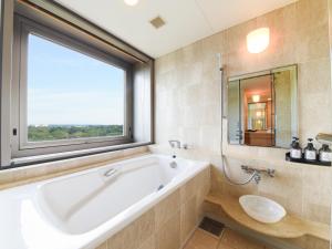 un bagno con ampia vasca e finestra di Forest Inn Showakan (Okura Hotels & Resorts) a Akishima