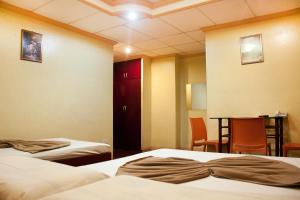 una camera d'albergo con due letti e un tavolo con sedie di Allson's Inn a Cebu City