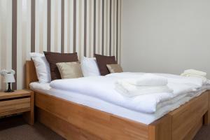 a neatly made bed with white sheets and pillows at Villa Cafe in Krnov