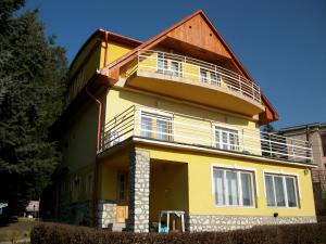 une maison jaune avec un balcon au-dessus dans l'établissement Szamóca Vendégház, à Miskolctapolca