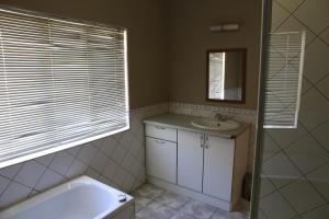 a bathroom with a tub and a sink and a mirror at Klein Windhoek Guesthouse in Windhoek +31 photos