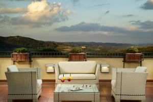 two chairs and a coffee table on a balcony at Mercure Petriolo Siena Terme Spa Hotel in Bagni di Petriolo