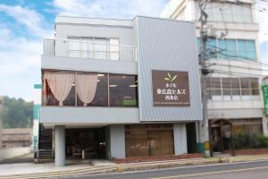 a white building with a sign on the side of it at Hotel Higashihiroshima Hills Saijo in Higashihiroshima