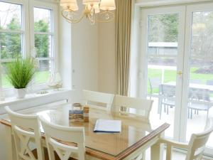 a dining room with a glass table and white chairs at Heidehüs Seepferdchen in Nebel