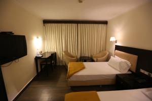 a hotel room with two beds and a television at Hotel La Castle in Chennai