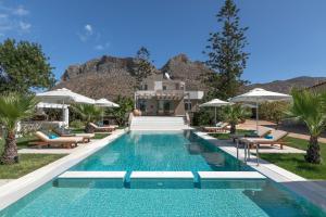 einen Pool mit Stühlen und Sonnenschirmen vor einem Haus in der Unterkunft Asterion Deep Blue Villa in Stavros