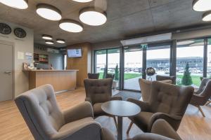 a waiting room with chairs and tables and windows at Air Hotel in Karmėlava
