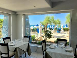 uma sala de jantar com mesas e cadeiras e uma grande janela em Hotel Blu em Porto Cesareo