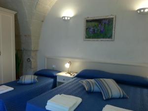 2 camas azules en una habitación con una pintura en la pared en B&B Demetra, en Carovigno