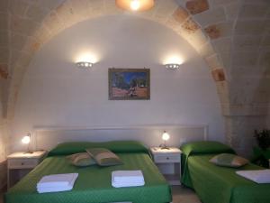 1 dormitorio con 2 camas verdes en una pared de piedra en B&B Demetra, en Carovigno