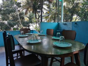 a wooden table with plates and glasses on it at Able Homestay in Thekkady